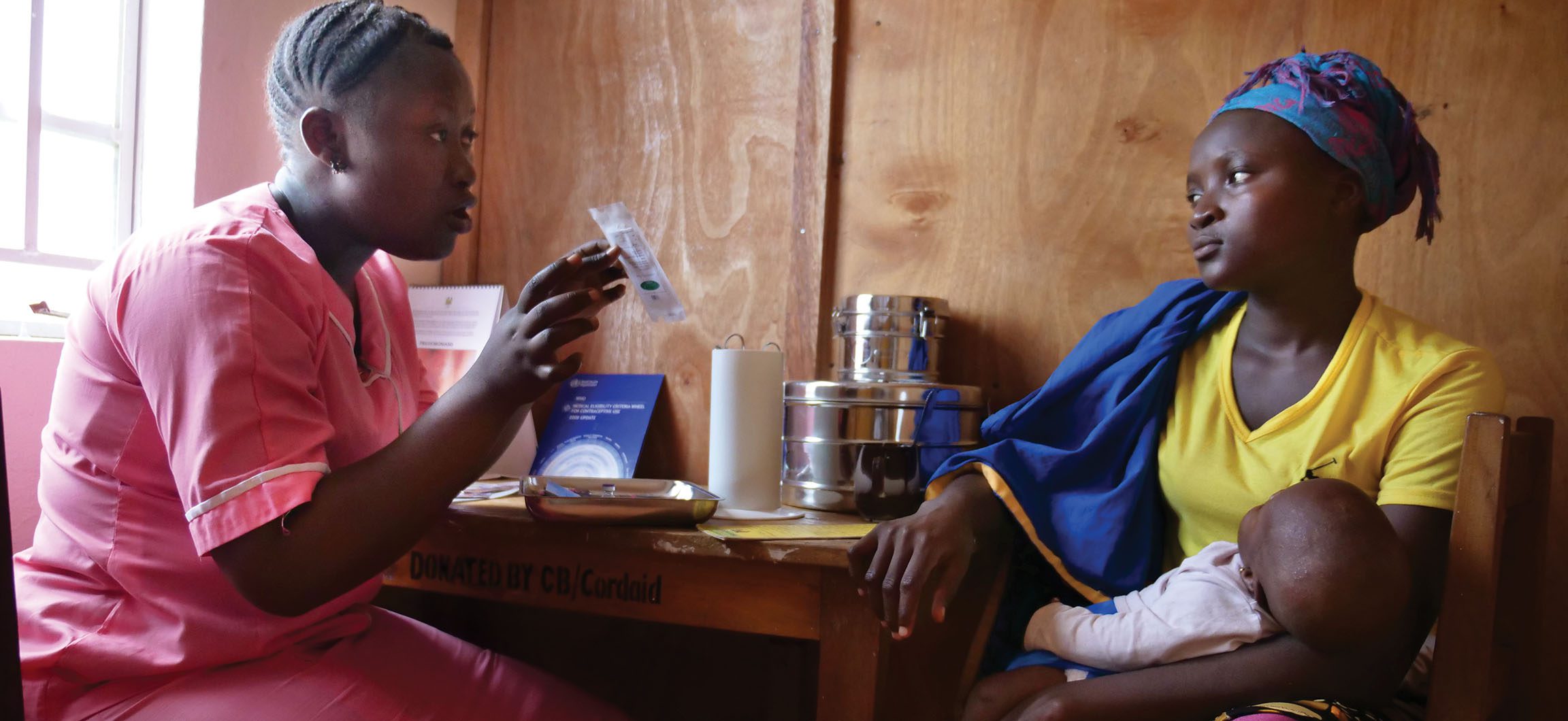 A healthcare worker advises a mother holding a child on nutrition.