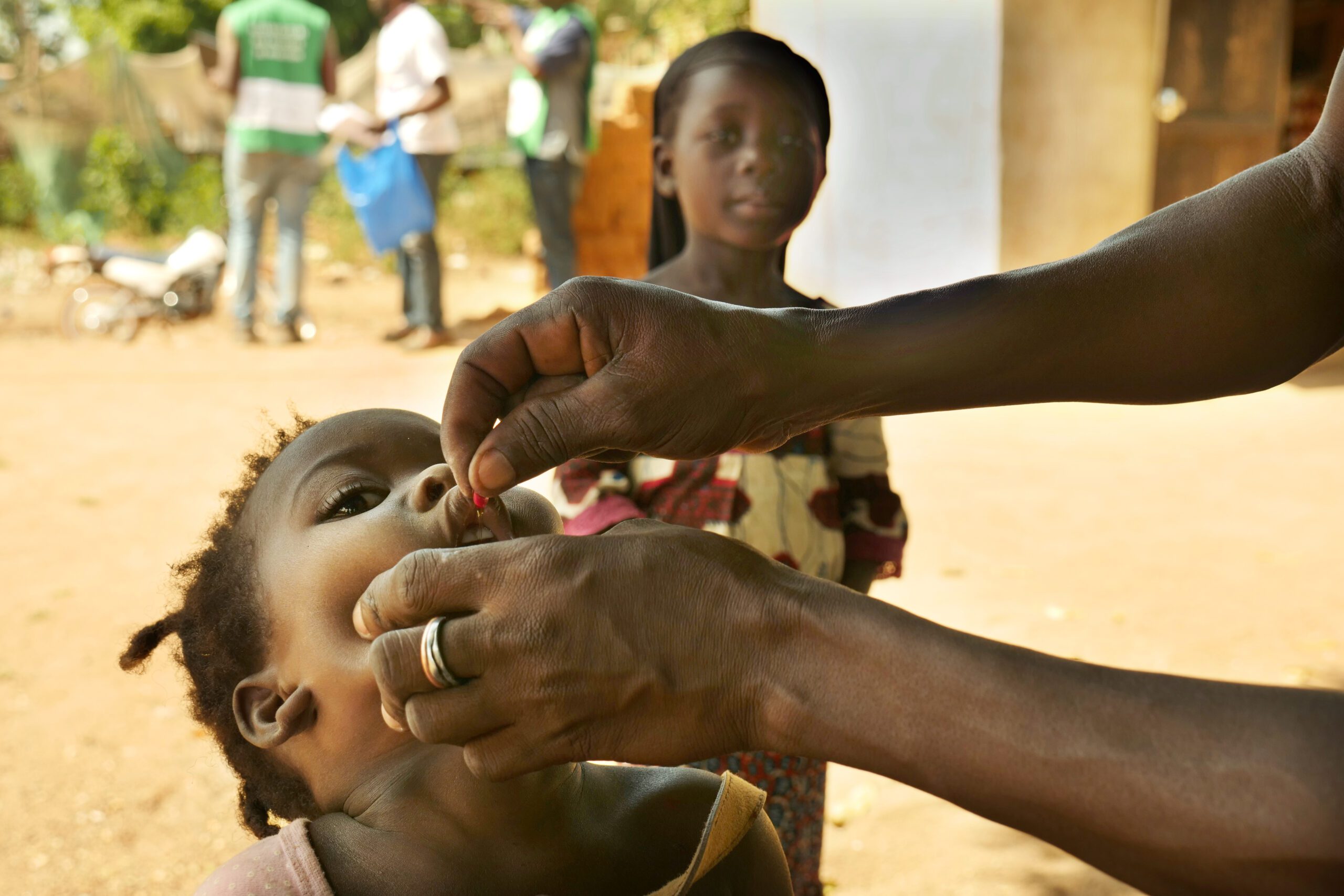 A child receiving a dose of Vitamin A from a health worker