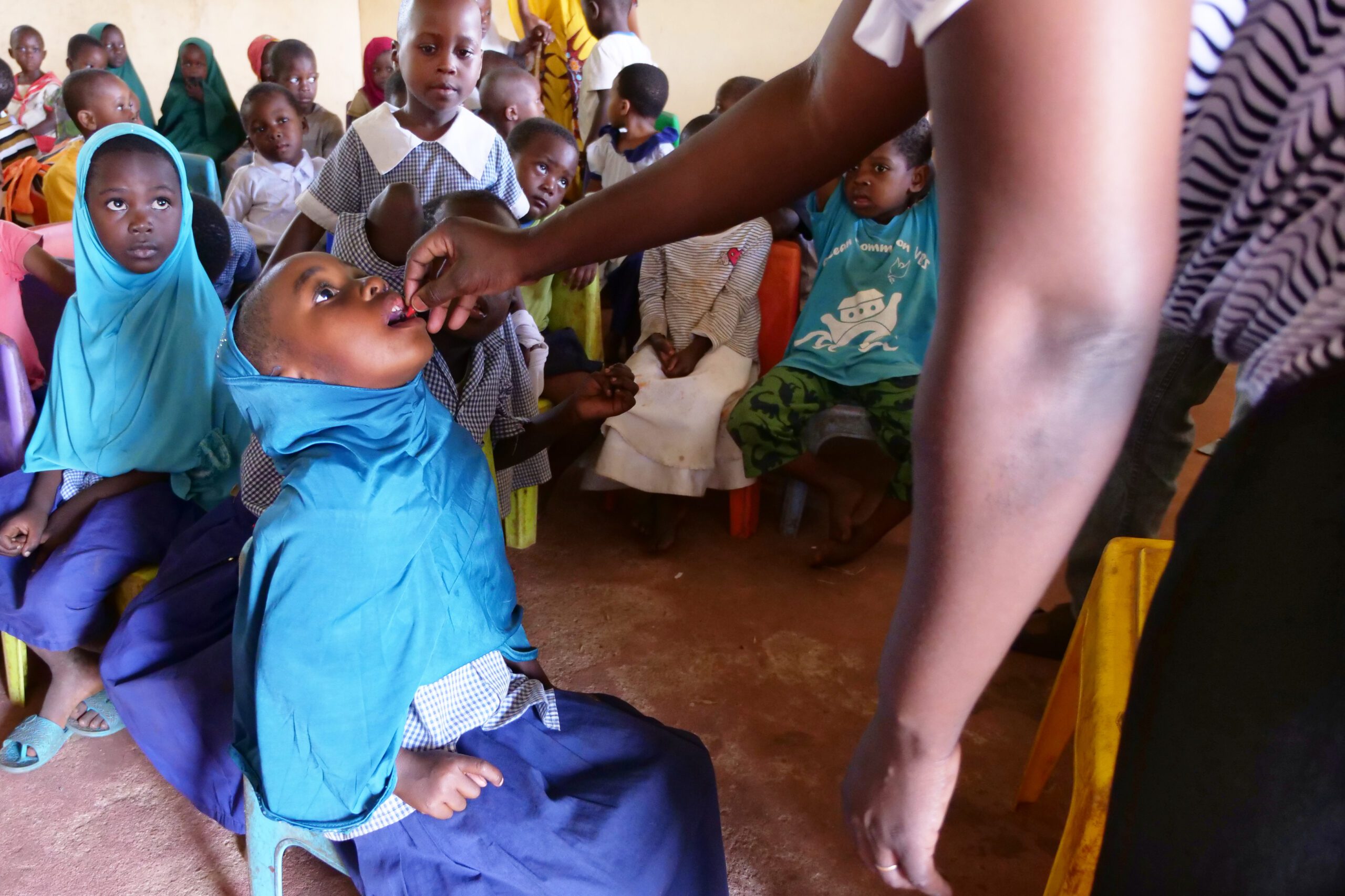 A girl at Funzi Island Primary School receives a dose of vitamin A supplementation as her classmates look on