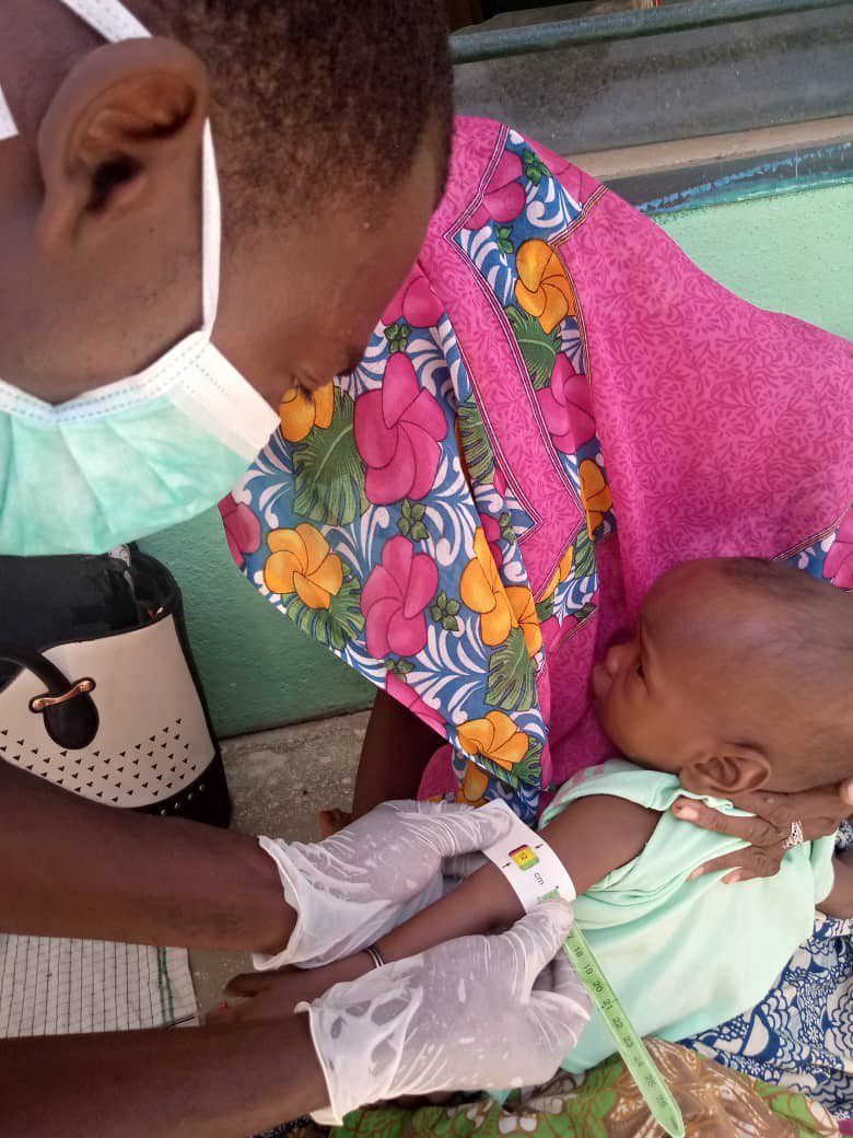 A community health worker measures an infant’s mid-upper arm circumference