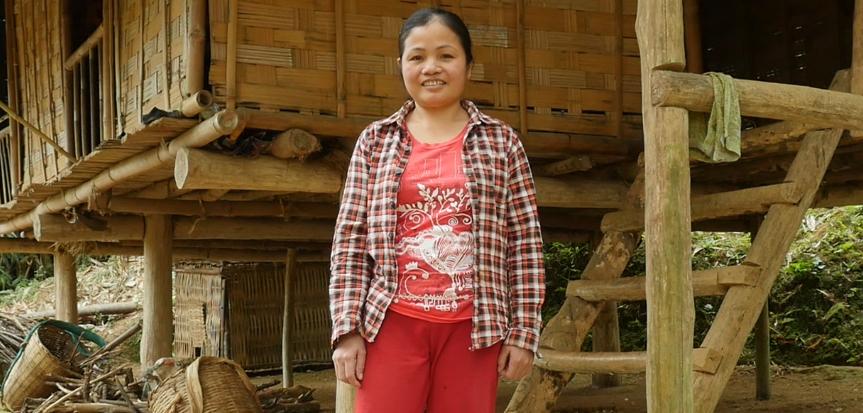 Ha Thi Theu stands in front of her home