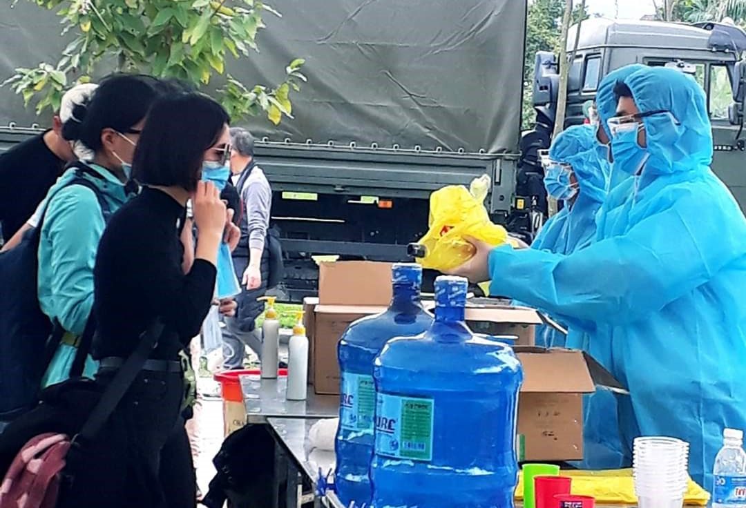 The Hoa Binh Center for Disease Control gives out soap and hand sanitizer to residents inside a quarantine area at a military base in Hoa Binh province