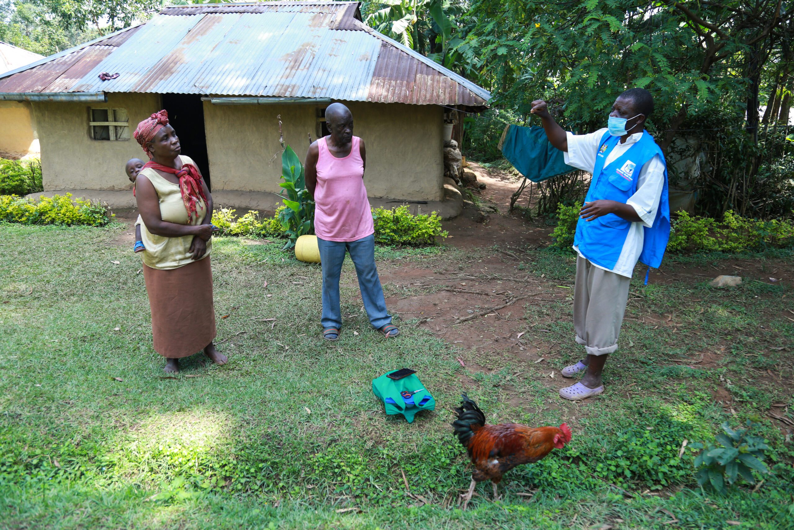 A health volunteer greets a family outside of their home.