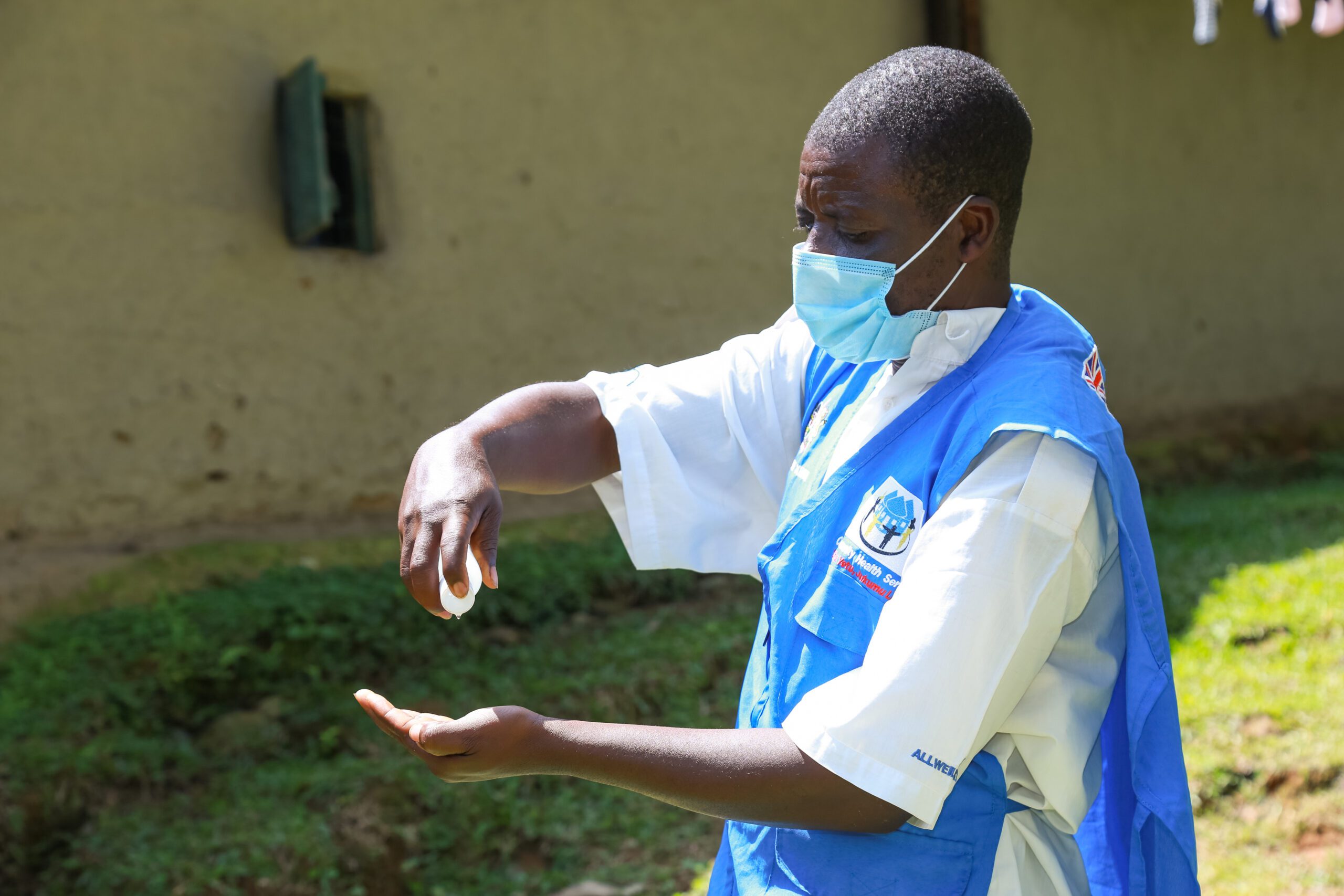 A health volunteer using hand sanitizer