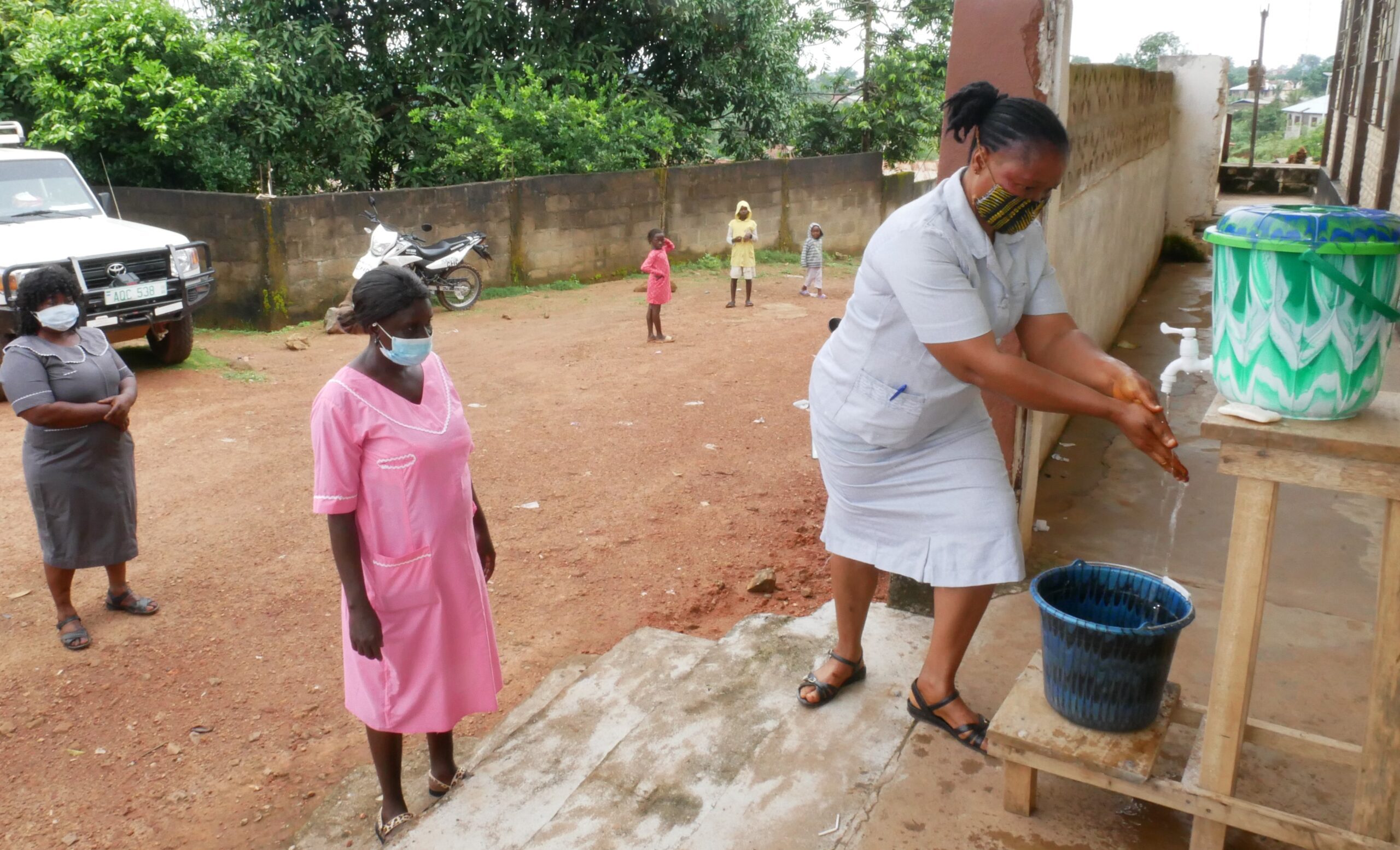 A health worker demonstrates how to use a handwashing station.