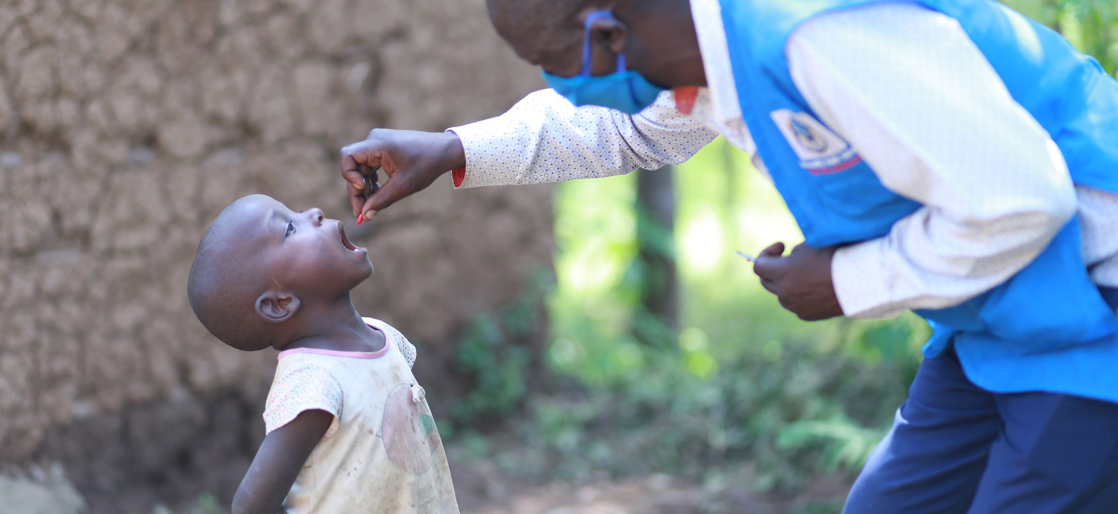 A health worker squeezes a dose of Vitamin A into a small child's mouth