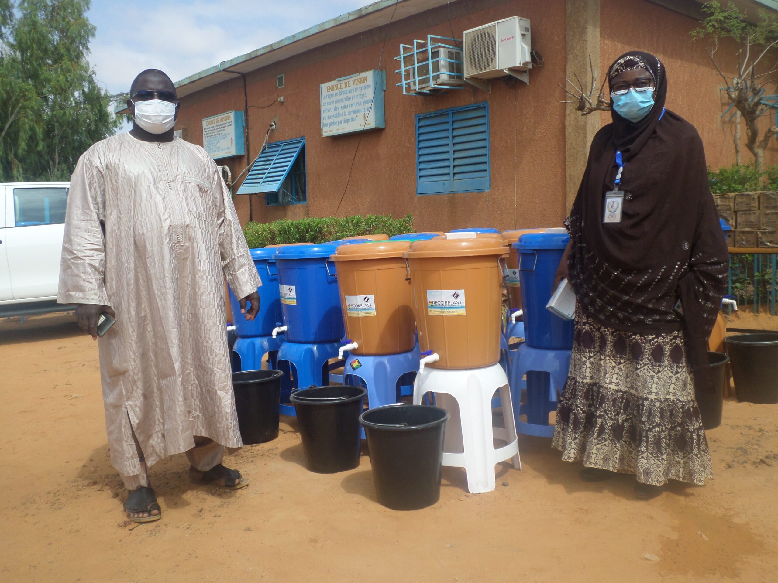 Health workers stand next to handwashing stations in Niger