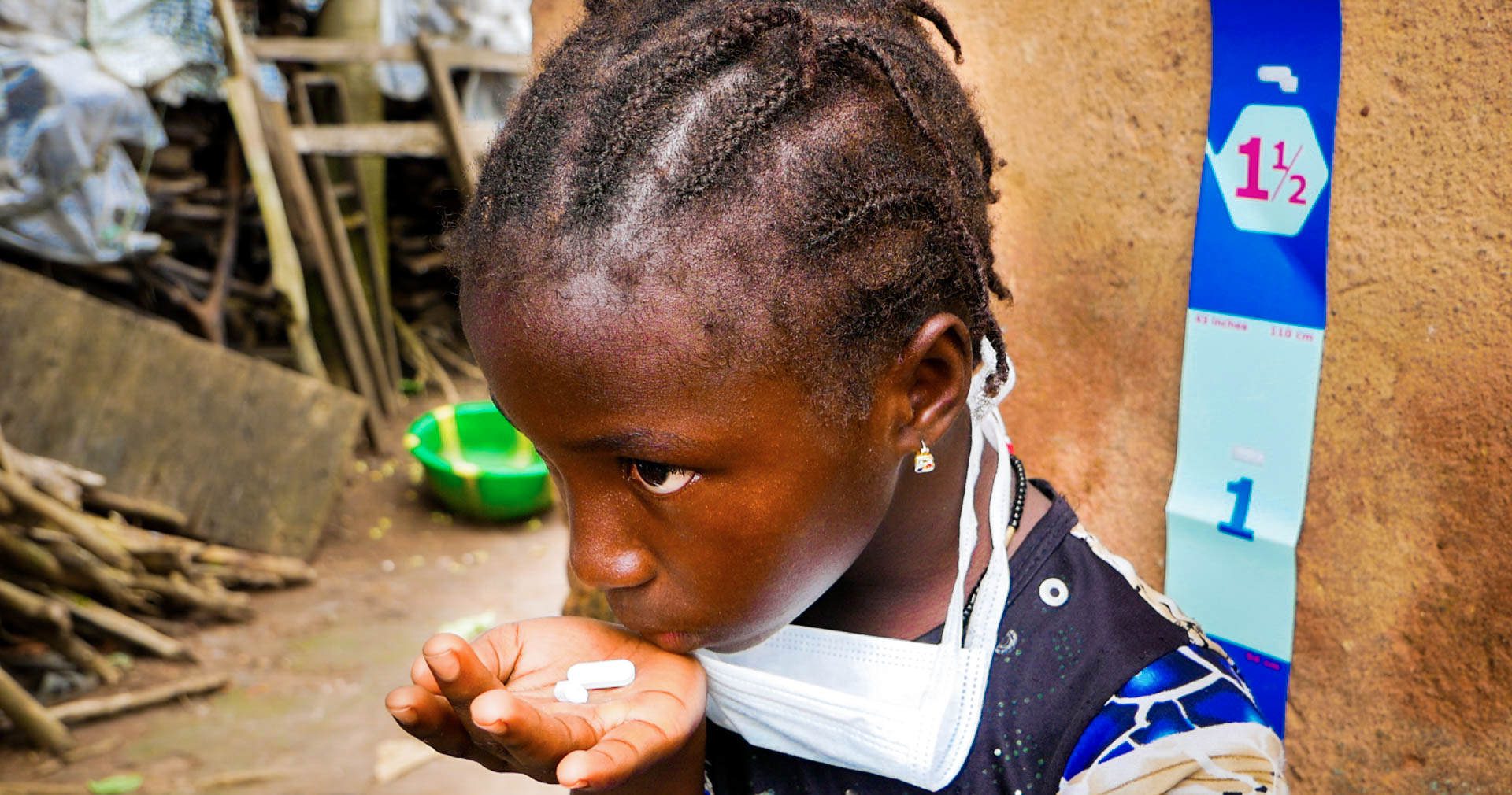 A young girl holds two pills, used to prevent and treat neglected tropical diseases.