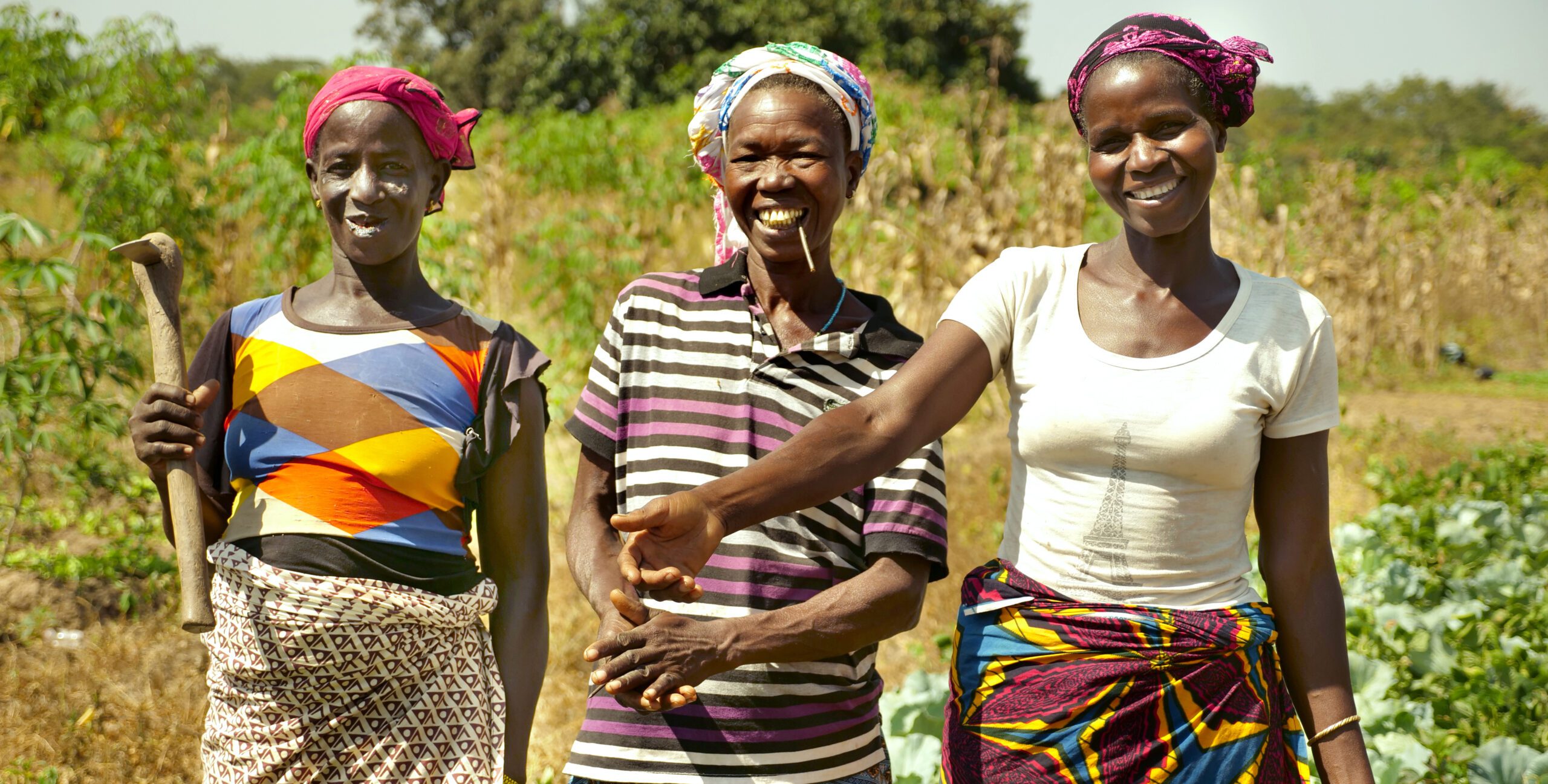 three women in a community garden smile