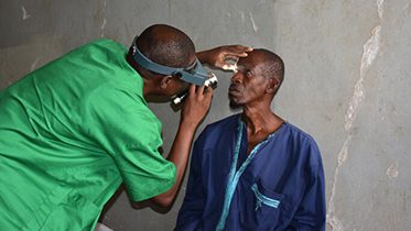 A health care worker examines the eye of a patient