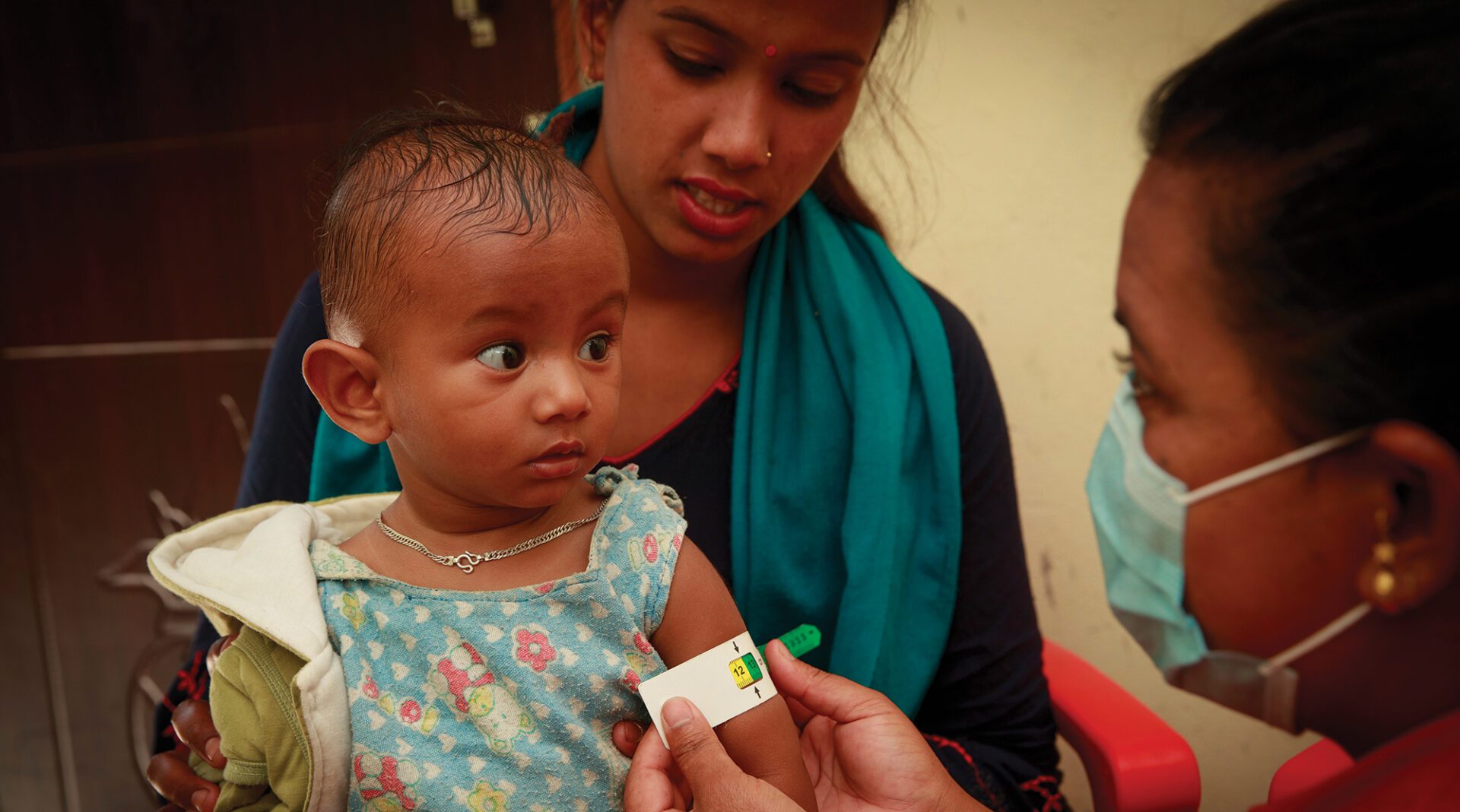 Health care worker measures a child for malnutrition.