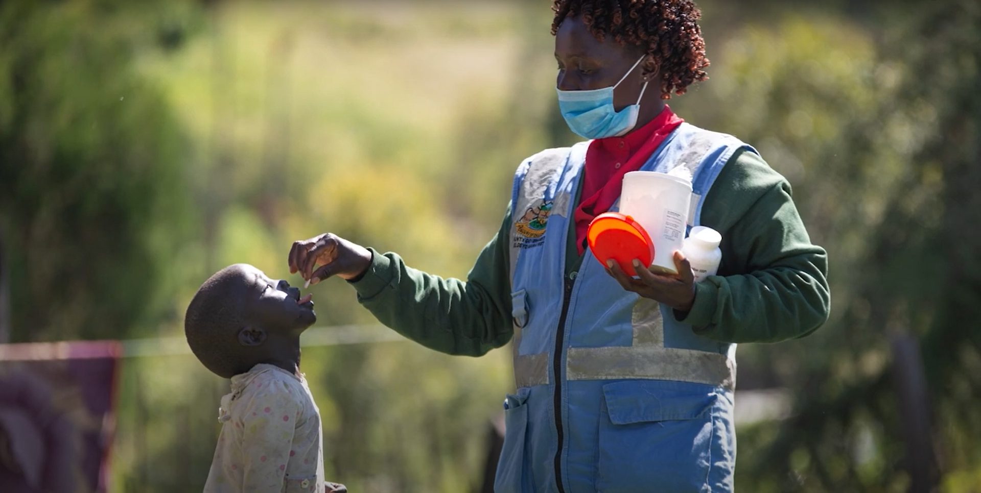 A healthcare worker administering vitamin A to a child.