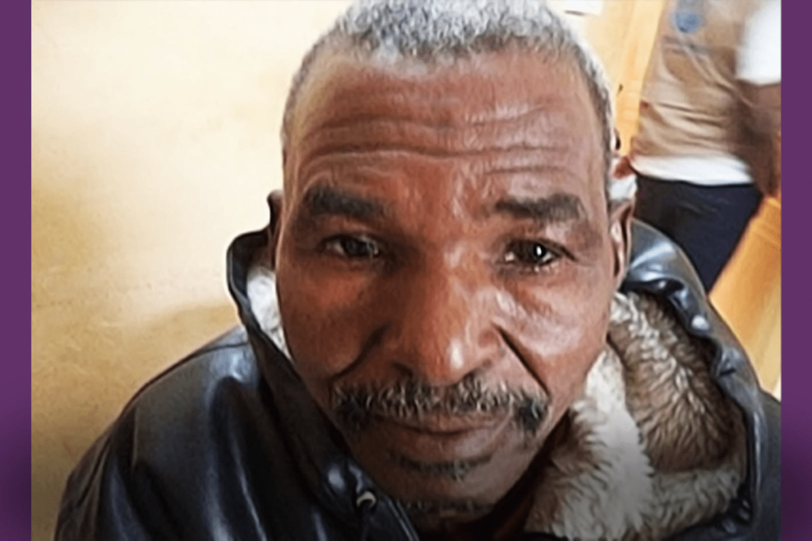 A older African man looks into the camera.