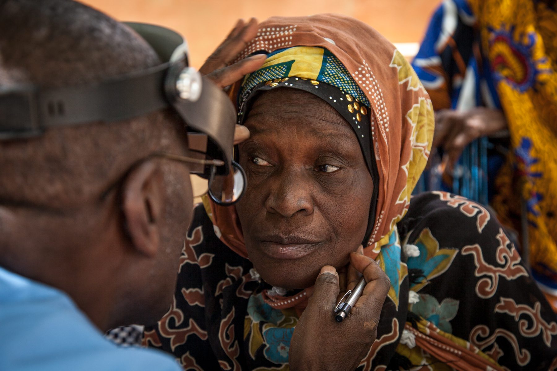 Healthcare professional examining woman's eyes during a medical examination.