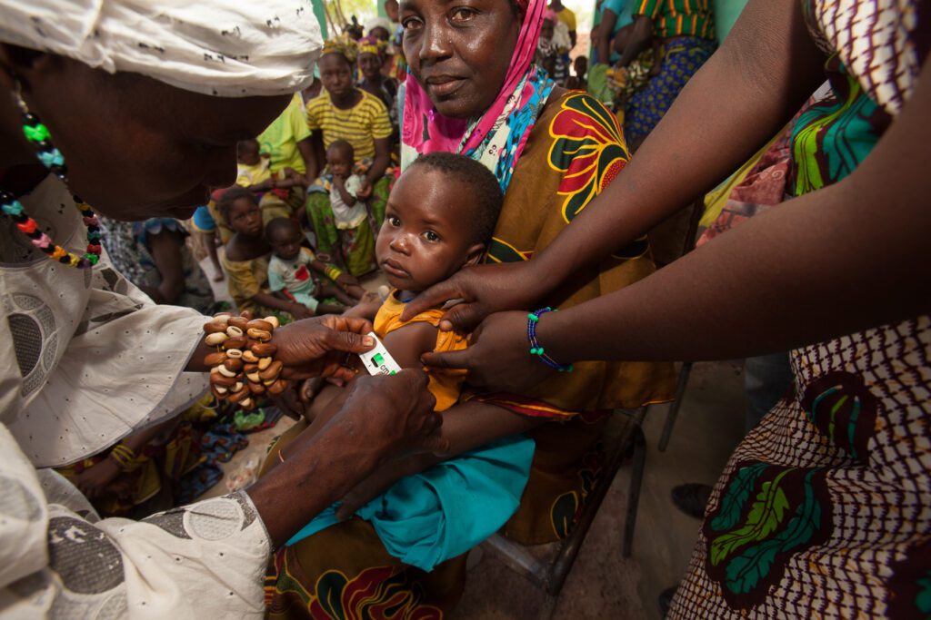 A healthcare professional measures a baby's arm circumference to check for malnutrition.