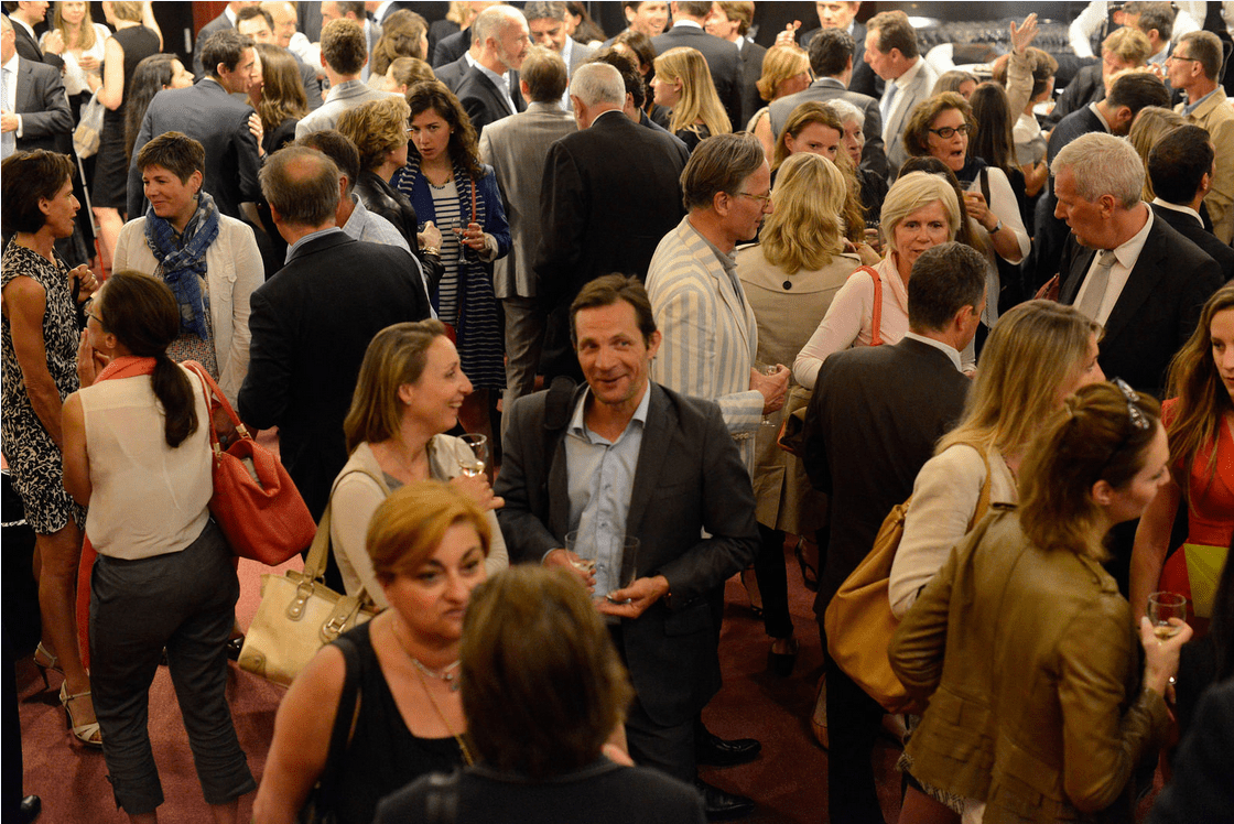 Diverse crowd of adults engaging in conversations at a busy networking event.