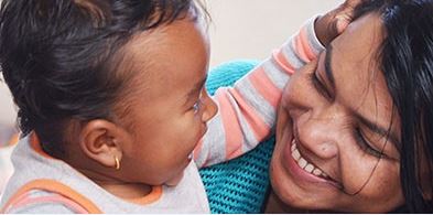 Happy mother engaging with her baby boy, sharing a joyful moment indoors.