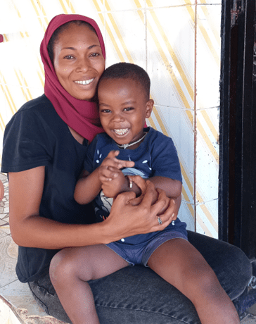 A Senegalese woman holds her young son in her lap.