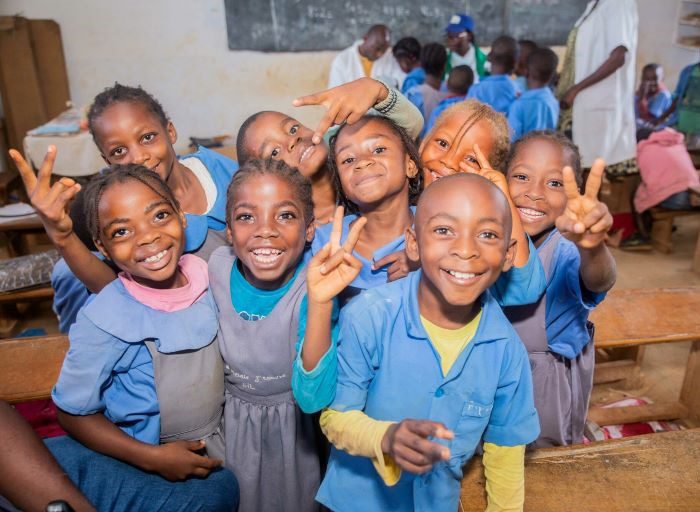 A group of school children in Cameroon smile for the camera.