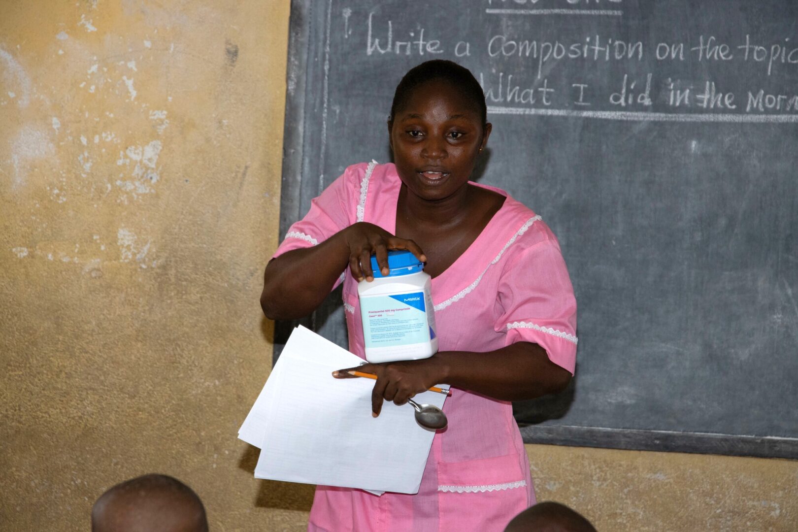 A female healthcare worker in Sierra Leone displays a large bottle of medication.