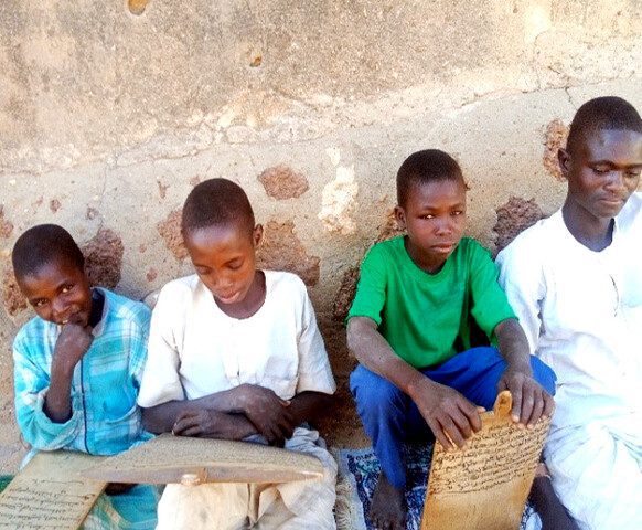 Boys reading wooden tablets outdoors