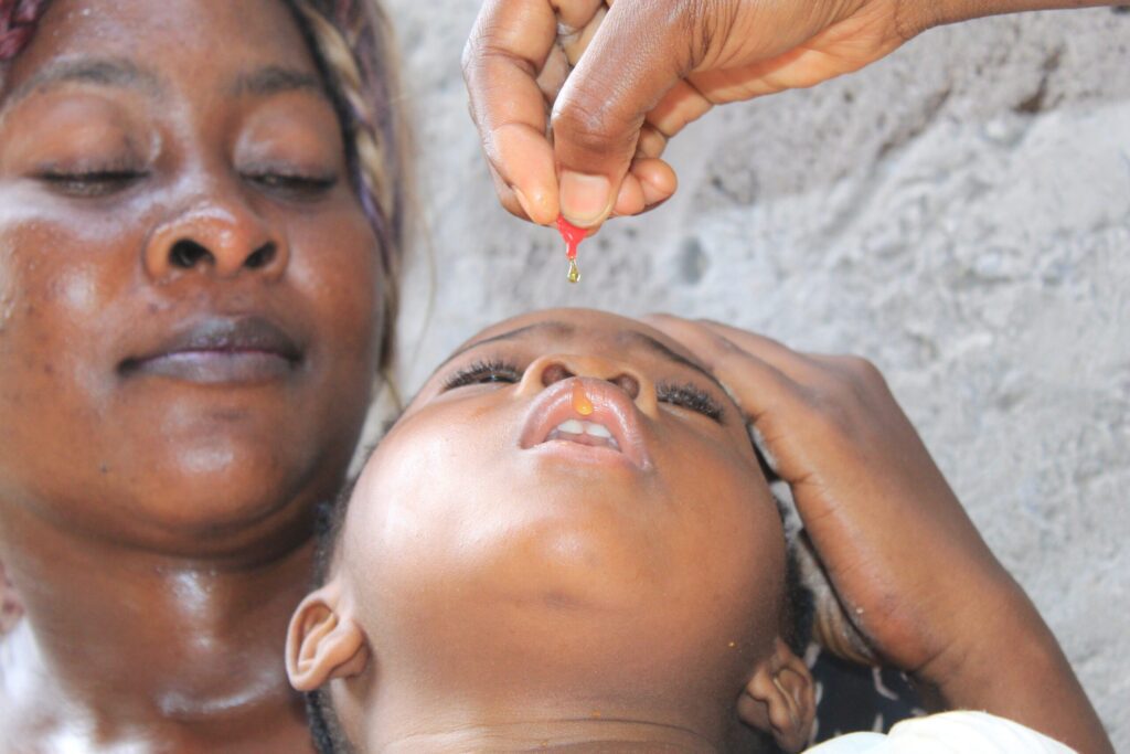 Close-up of a woman giving vitamin A supplementation to child.