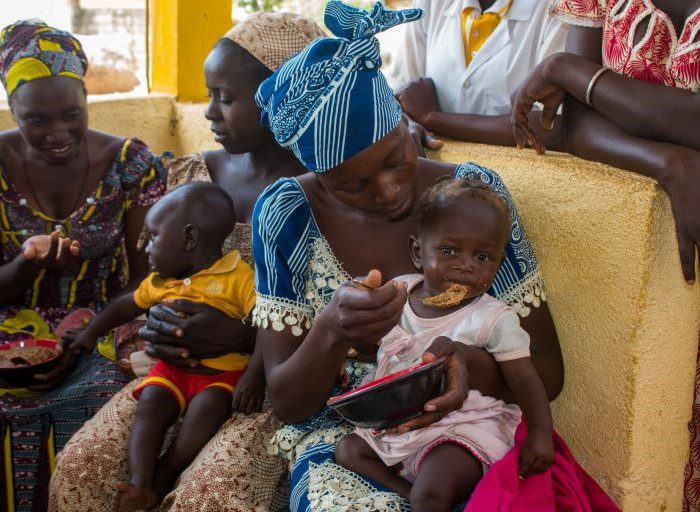 A Cameroonian woman feeds a baby girl porridge.