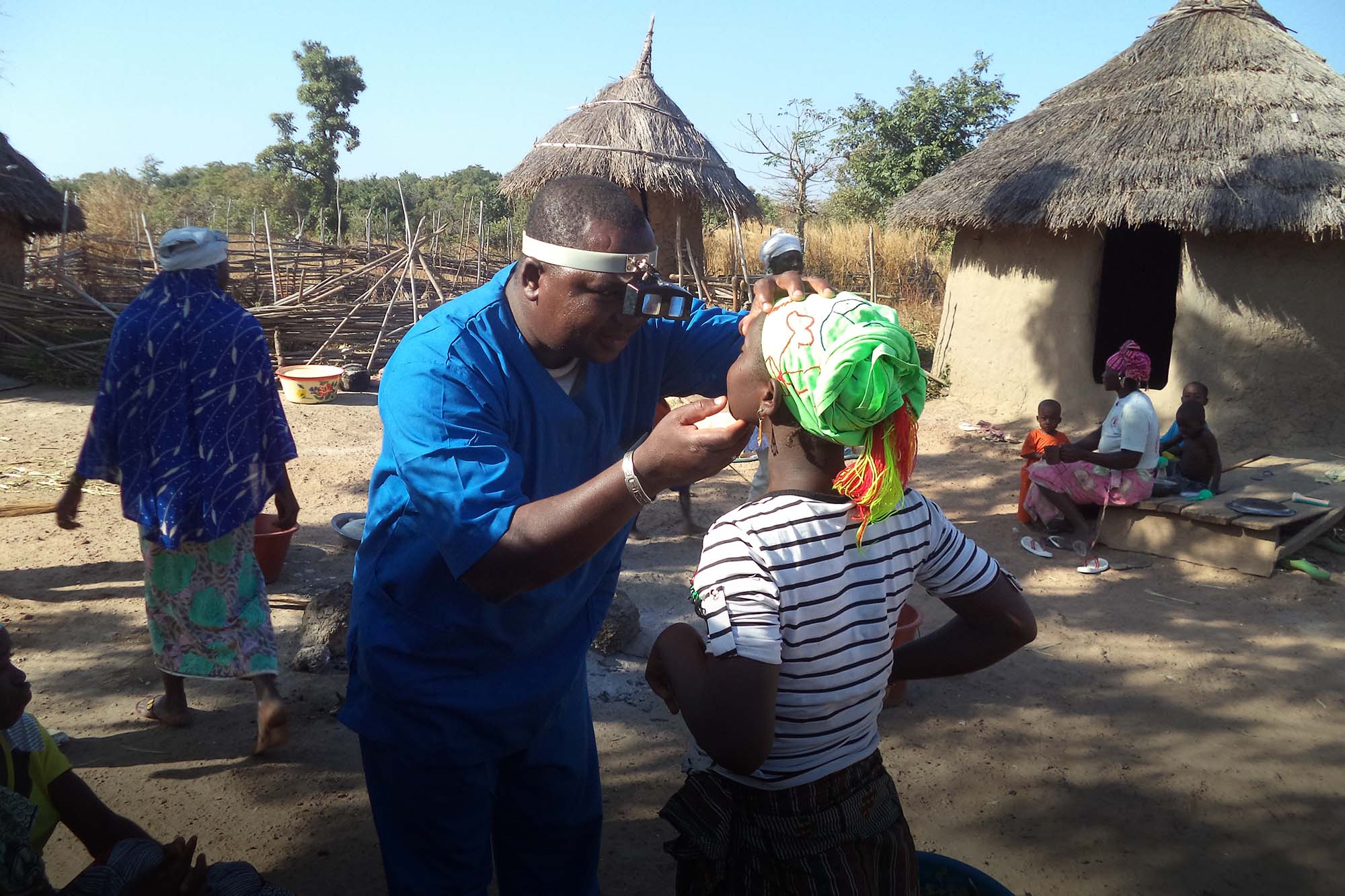 A doctor in Mali examines a woman's eyes.
