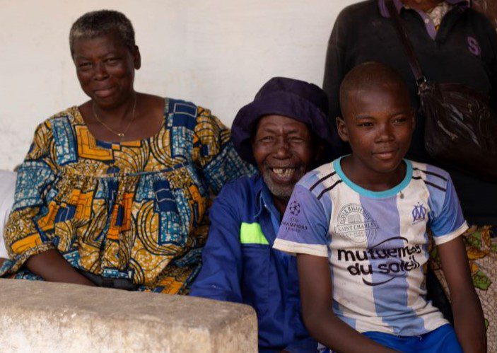 An older Cameroonian woman and man sit with a younger boy.
