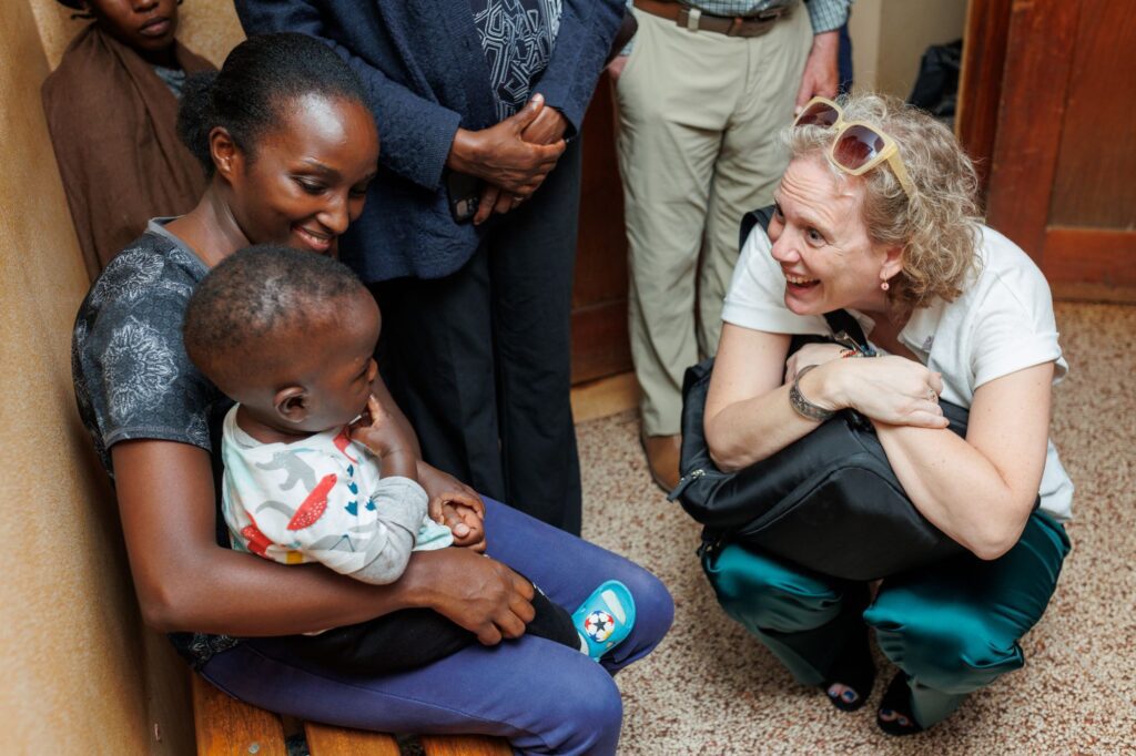 Sarah Bouchie (right) kneels down to speak to a Kenyan mother and her young son.