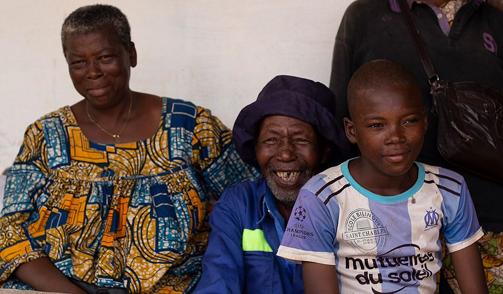 A group of individuals seated on a bench, reflecting a moment of community and shared experience.