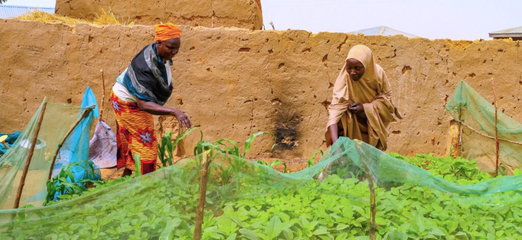 Two women work in a garden focused on climate-smart agriculture.