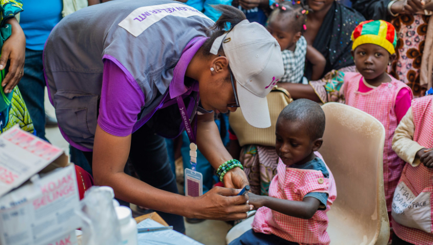 Health worker measuring child's arm for nutrition check