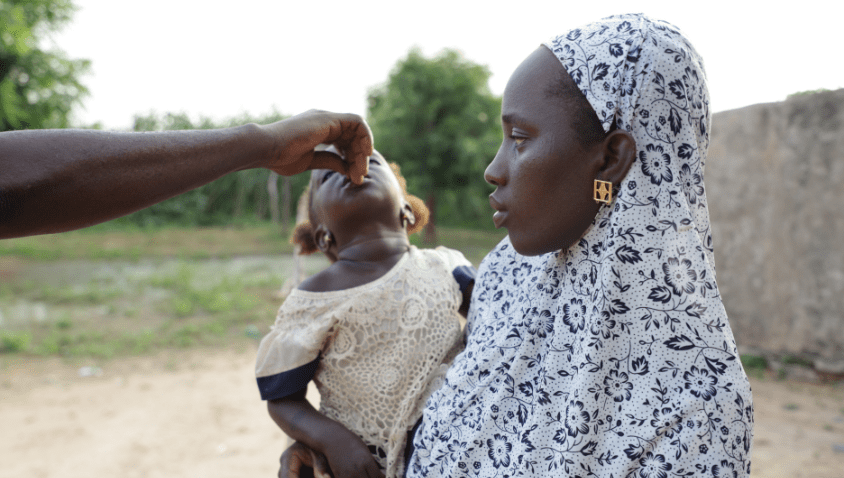 Mother giving health supplement to child outdoors