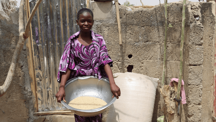 Woman with bowl of grain outdoors