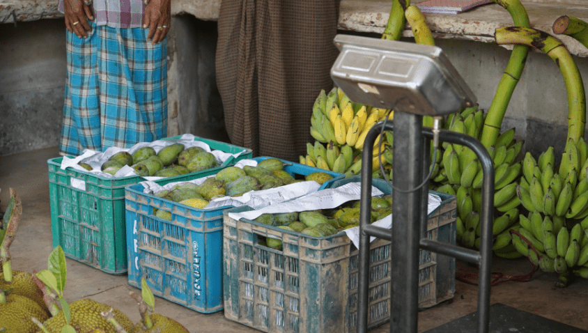 Vendors weighing fresh mangoes and bananas