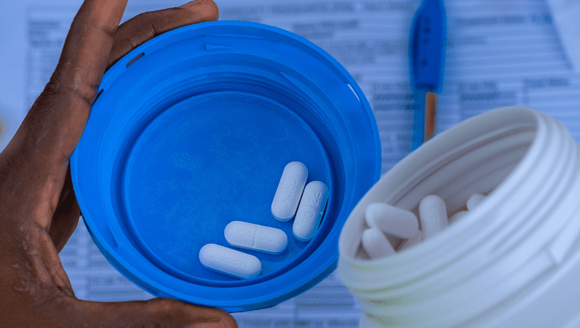 Hand holding blue pill container with medication.