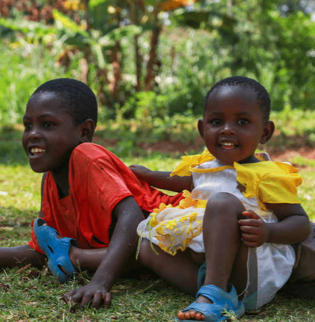 Two kids laughing and playing on grass