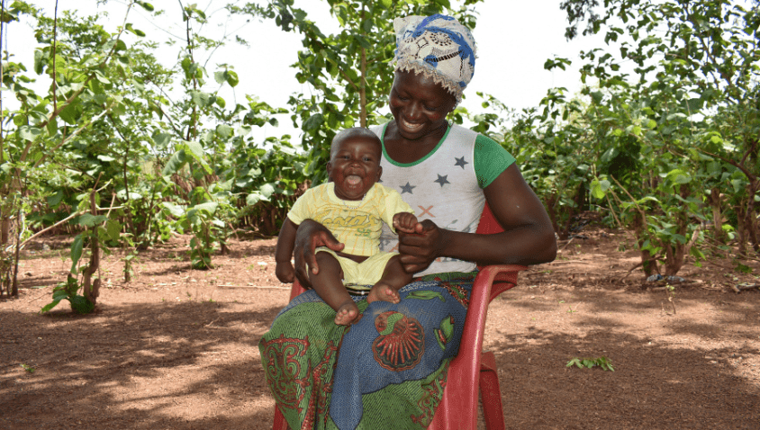 Woman and child smiling in garden.
