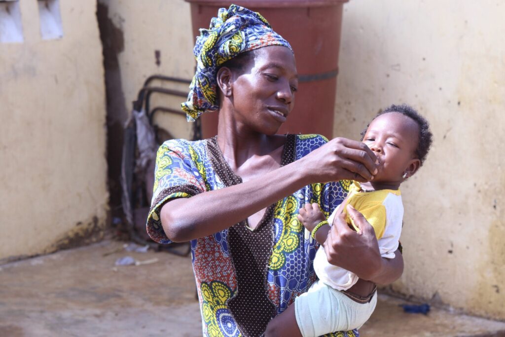 A woman gives a baby medicine.