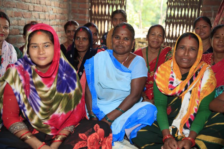 Women in colorful sarees smiling together