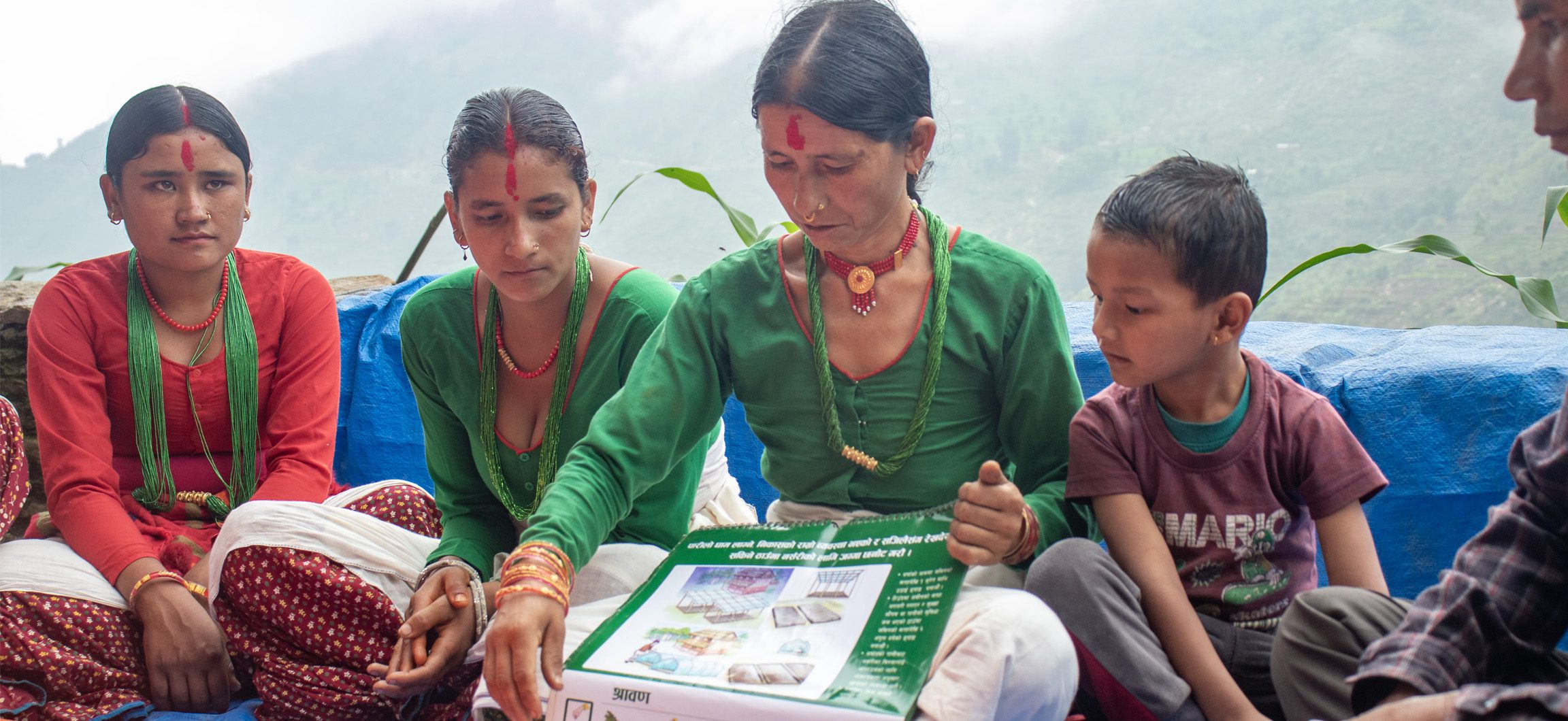 A woman in Nepal displays a diagram of climate-smart agricultural techniques to a group of people.
