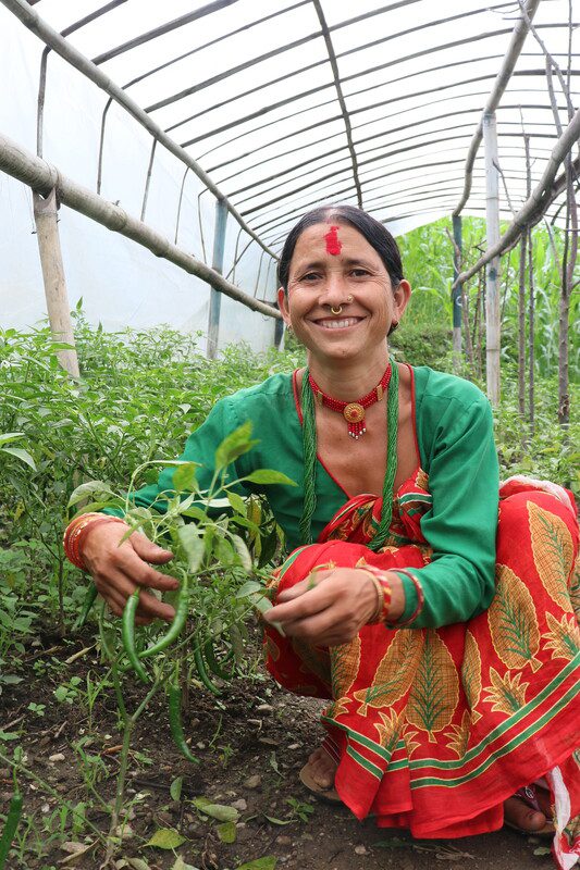 A woman in Nepal shows off her crops in a polyhouse.