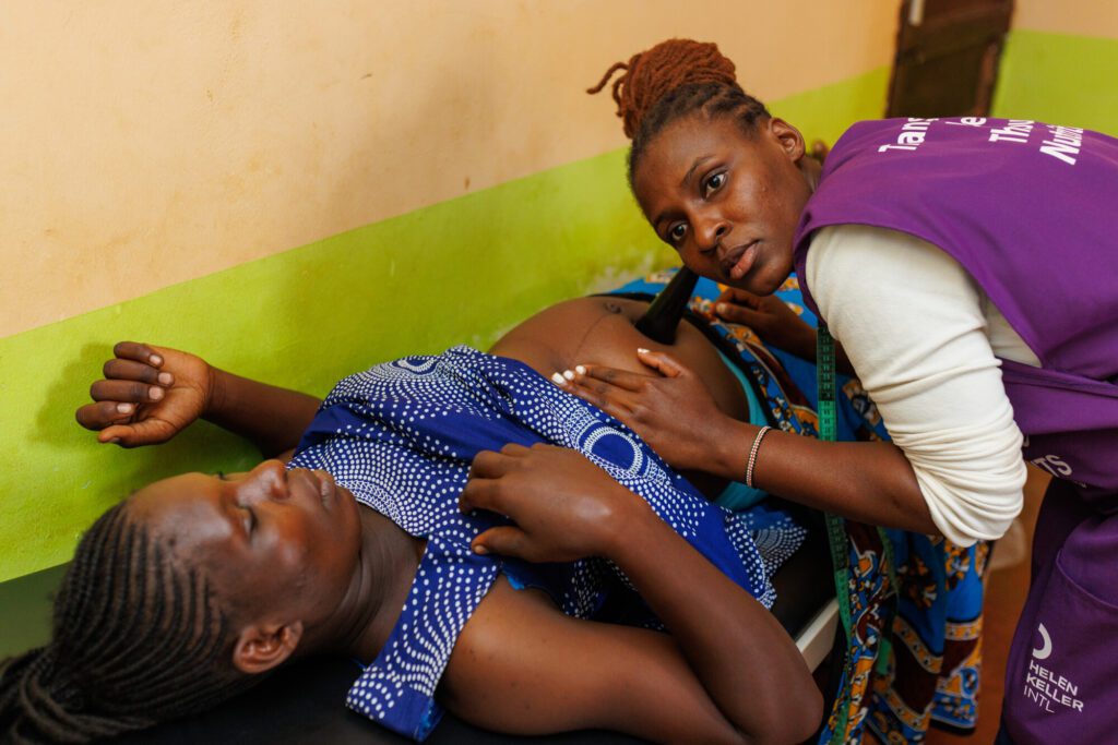 Health worker checking pregnant woman's abdomen