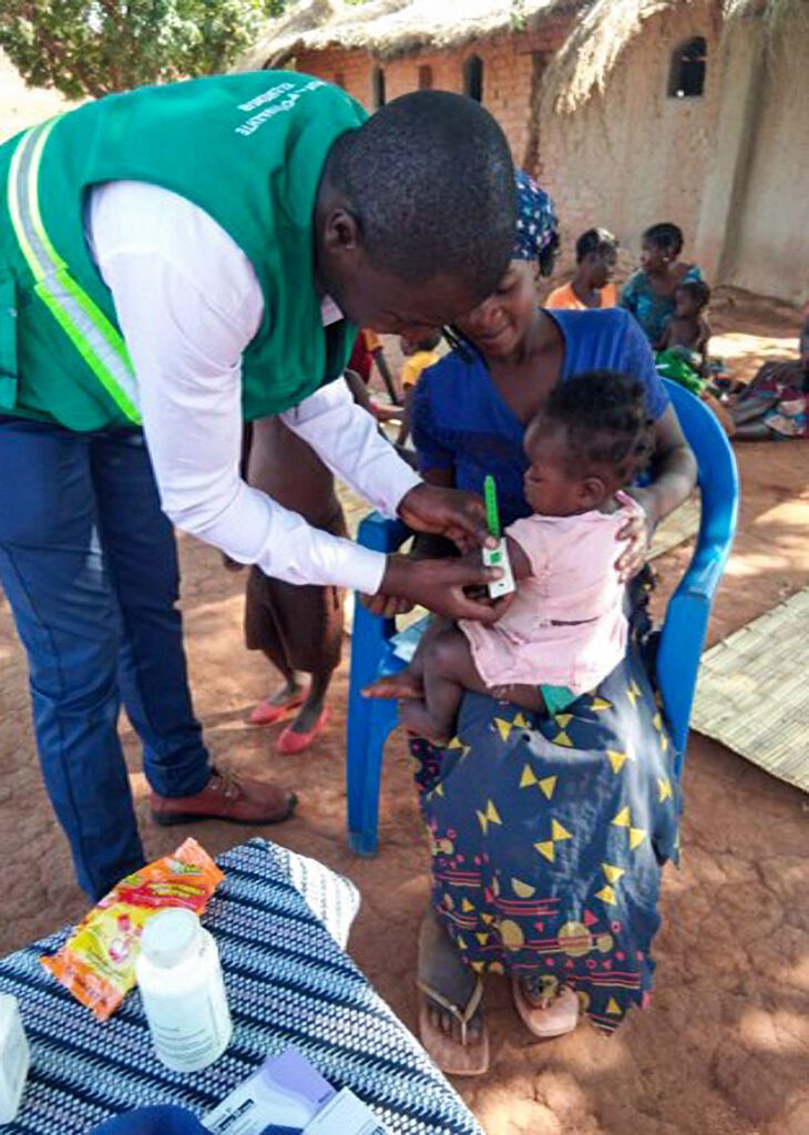 A community health worker screens a girl for malnutrition.