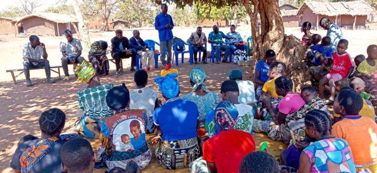 Outdoor community meeting with speaker and audience