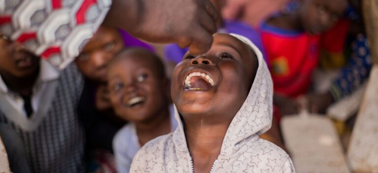 Child smiling while receiving vitamin A supplement.