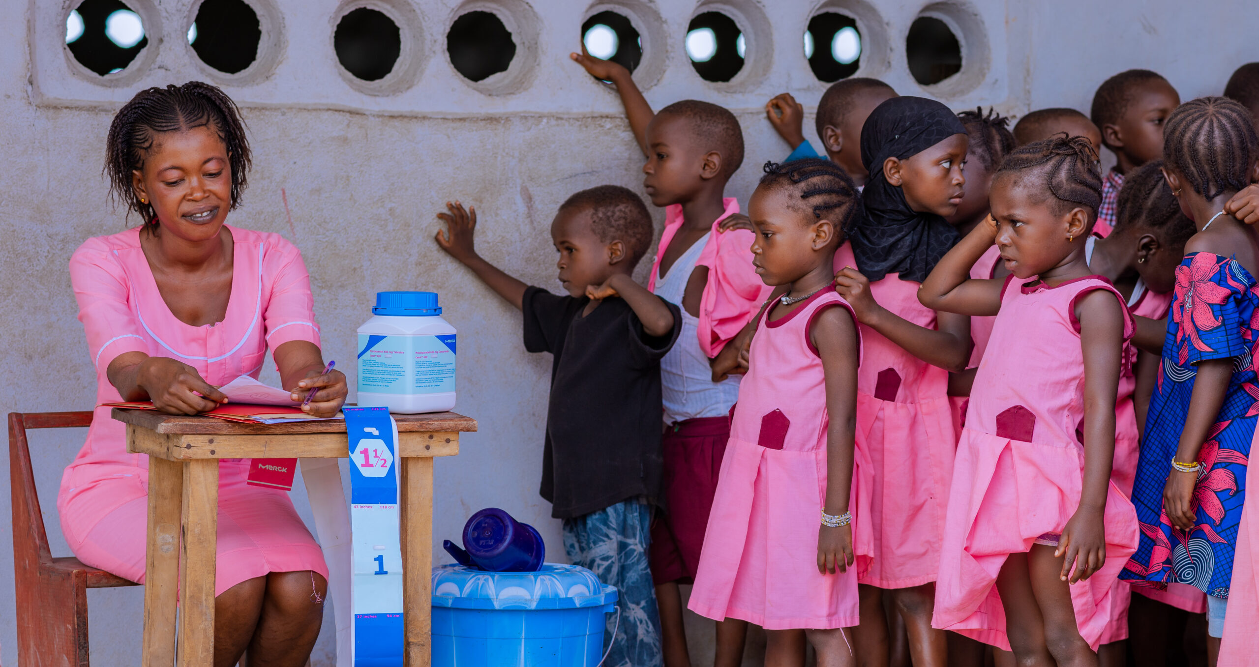 Children lined up to receive schistosomiasis treatment from a community health worker.