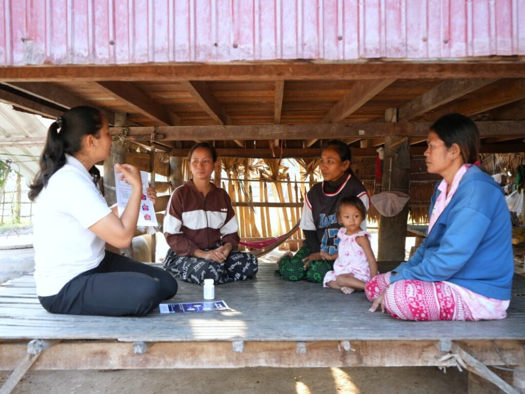 A community health worker discusses prenatal vitamins with three pregnant women in Cambodia.