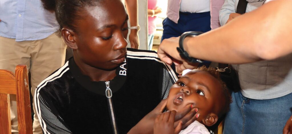Child receiving oral vaccine from healthcare worker